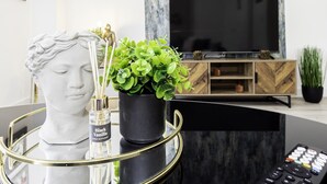 A modern living room with a marble coffee table, a bust sculpture, a potted plant, and a television set. - Charming 3-bedroom House in Balsall Heath, Birmingham (Birmingham)