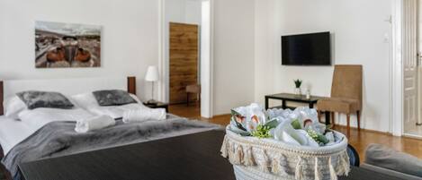 A modern hotel room with a bed, a television, a small table, and a decorative plant.