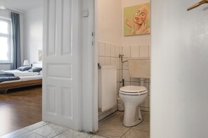 Ein Schlafzimmer mit Bett, ein Badezimmer mit Toilette und eine Tür zu einem anderen Raum.