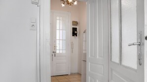 A hallway with white doors, a light fixture, and a tiled floor. - Comfy 2BR Apartment Long Stay Downtown (Vienna)
