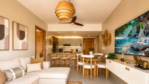 Una sala moderna con sofá, mesa de comedor, sillas y una cocina al fondo.