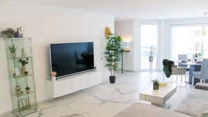 Un salon moderne avec un téléviseur à écran plat, une vitrine, une plante en pot, une table basse et un canapé.