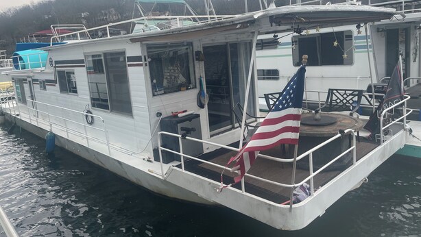 Ein festliegendes Boot mit überdachtem Deck, einer Flagge und einer Kabinenstruktur.