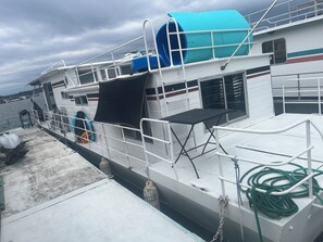 Ein Boot mit überdachtem Deckbereich, einem Rettungsring und einem an der Seite aufgerollten grünen Schlauch.