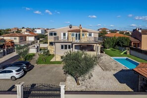 A two-story house with a swimming pool, a covered patio, and a driveway with parked cars. - Oasis Jadreski Apartments (Liznjan)