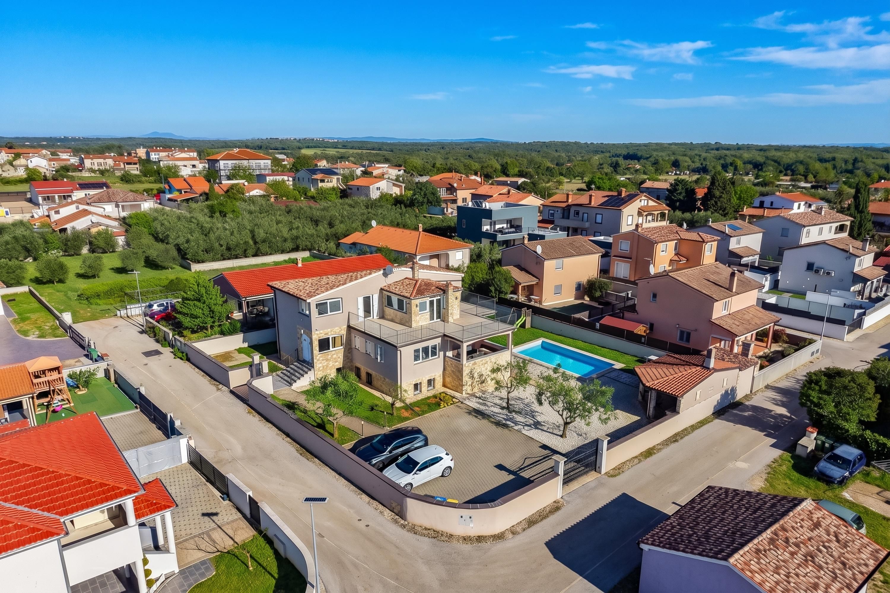 A residential area with modern houses, a swimming pool, and a clear sky.