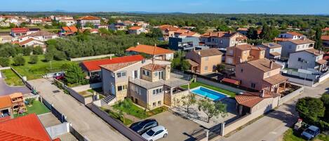 A residential area with modern houses, a swimming pool, and a clear sky.