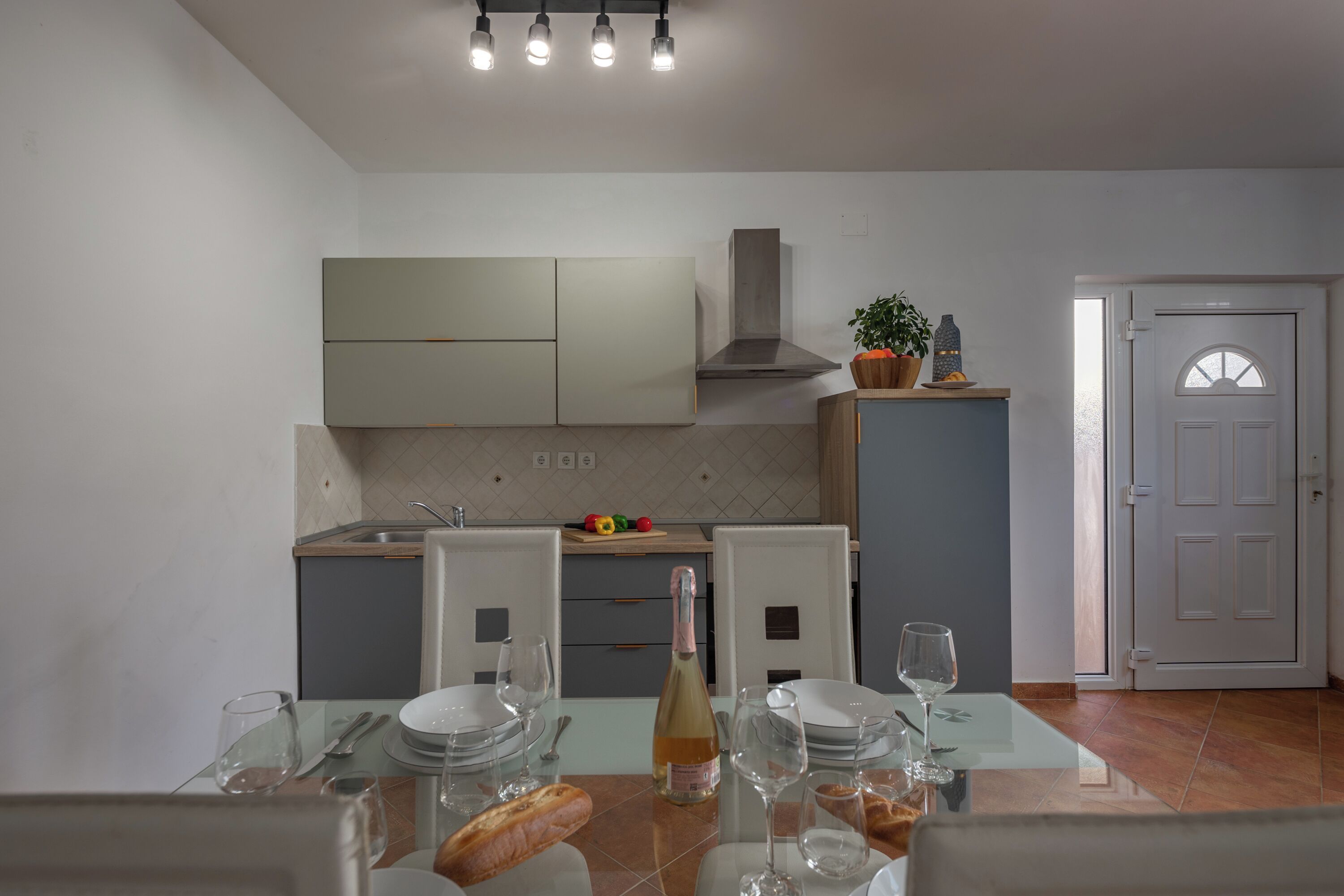 A modern kitchen with white cabinets, a built-in oven, and a dining area with a table set for two.