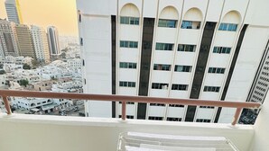 En balkong med ett torkställ, ett kaklat golv och utsikt över en stadssiluett med höga byggnader.