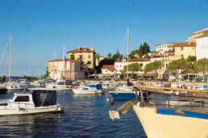 Un puerto deportivo con varias embarcaciones amarradas, rodeado de edificios con balcones y árboles.