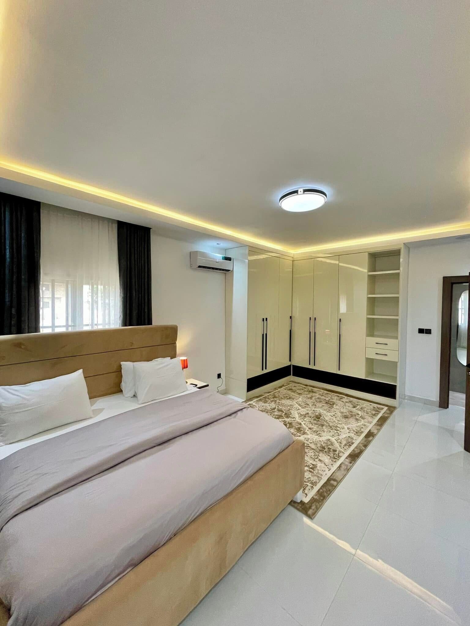 Une chambre moderne dotée d’un grand lit, d’un dressing et d’un appareil de climatisation.