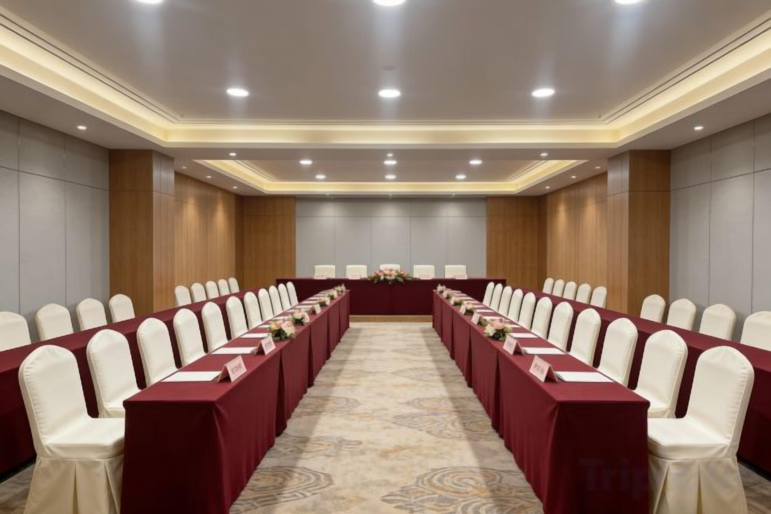 A conference room with a long table, rows of chairs, and a carpeted floor.