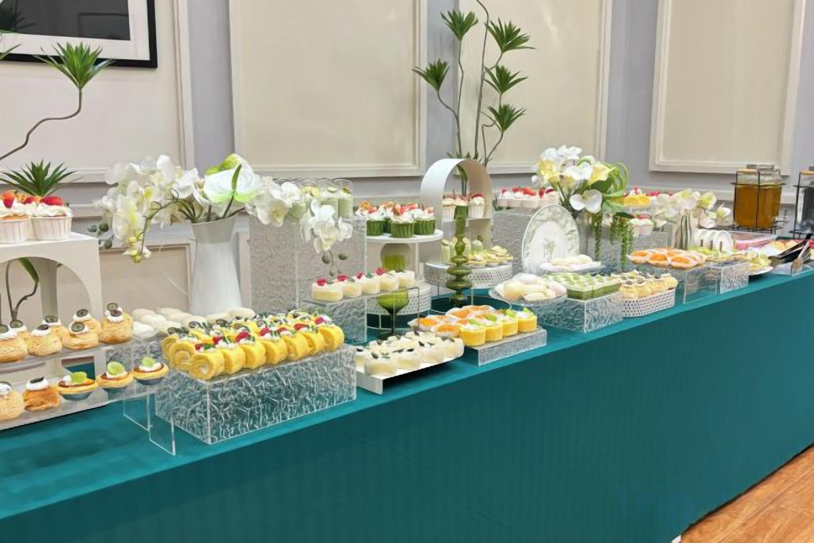 A buffet table with various food items and floral decorations.
