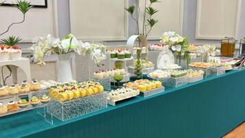 A buffet table with various food items and floral decorations.