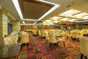 Un vestíbulo de hotel con varias zonas de estar, un mostrador de recepción y una alfombra estampada.