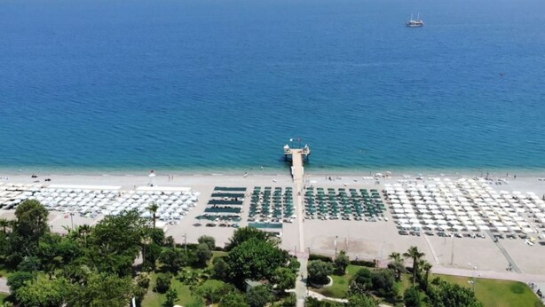 An aerial view of a beach with rows of umbrellas and a pier extending into the sea. - Elit Life Hotel - All Inclusive (Kemer)