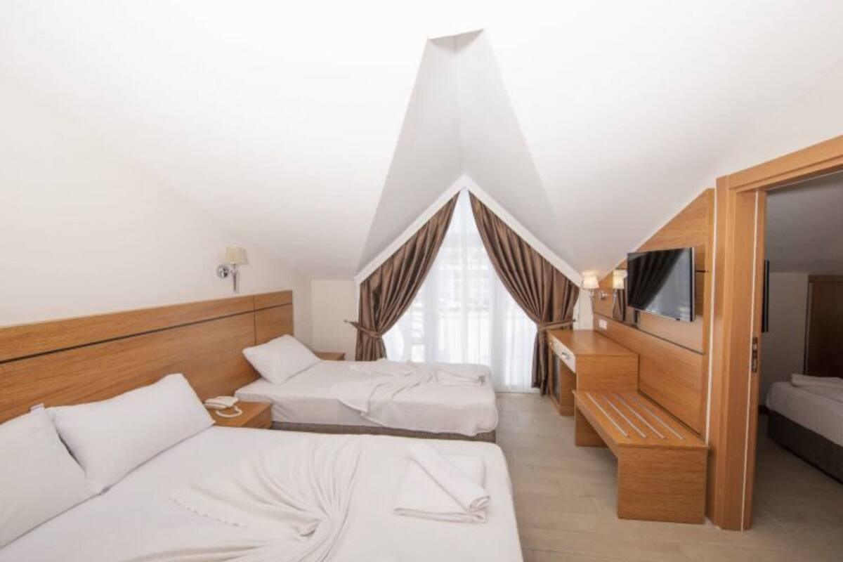 A hotel room with two beds, a TV, and a wooden bench.