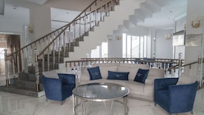 A spacious living area with a modern staircase, a round glass coffee table, and a sofa with blue cushions. - Elit Life Hotel - All Inclusive (Kemer)