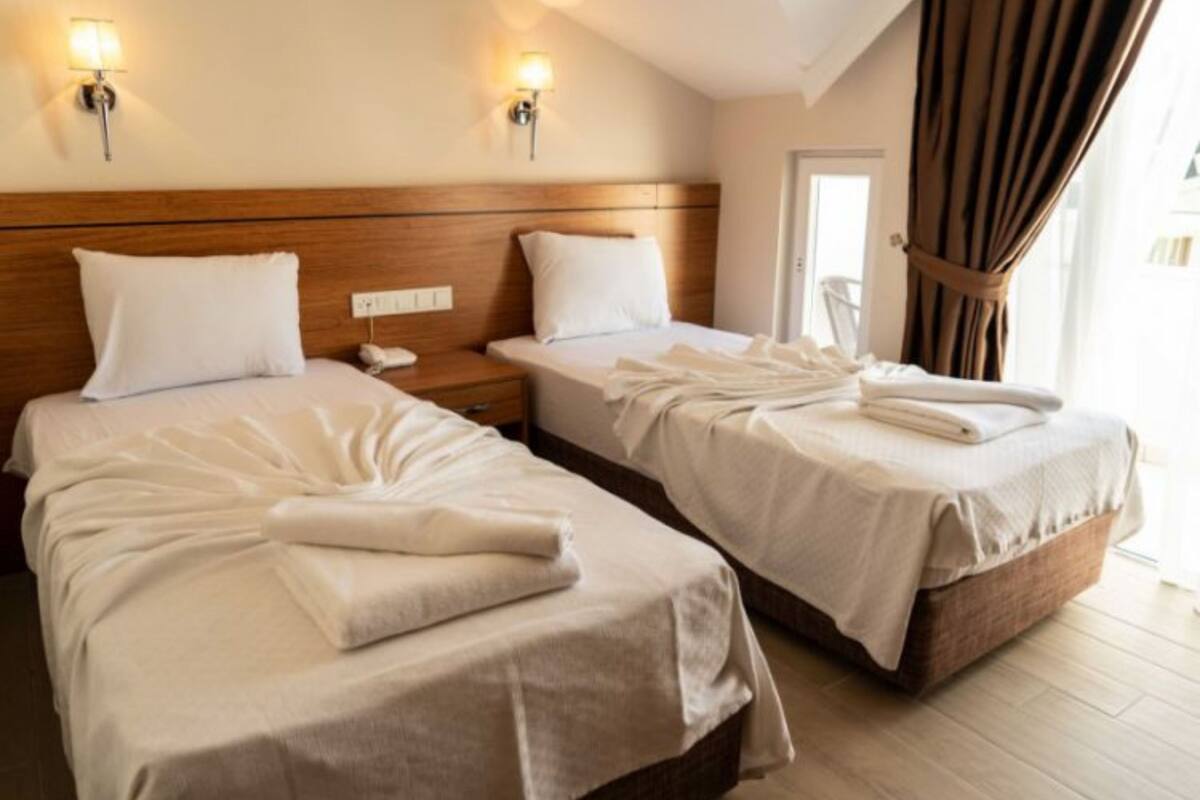 A hotel room with two beds, each with a wooden headboard, white bedding, and a nightstand with a phone.