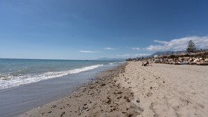 Une plage avec un ciel dégagé, un rivage sablonneux et quelques parasols.