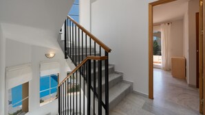 Un escalier moderne avec des rampes noires et des garde-corps en bois, menant à une pièce offrant une vue sur une piscine.
