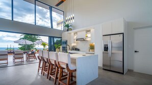 Una cocina moderna con una isla grande, taburetes de bar y un refrigerador de acero inoxidable.