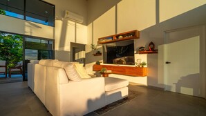 Una sala de estar moderna con un sofá grande, una consola de madera y un televisor montado en la pared.