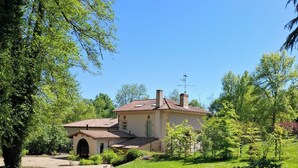 Una casa con camino de grava que conduce a un césped verde y un pequeño jardín.