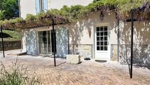 Un edificio con patio de ladrillo, fachada blanca y entrada cubierta con puerta.