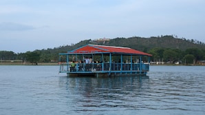 A blue boat with a red roof on a calm body of water.