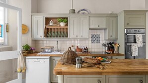 Una cocina con armarios blancos, encimera de madera, lavavajillas y horno.