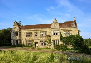 A large, historic stone building with multiple windows and a prominent entrance. - Haremere Hall - A Jacobean Estate of Grandeur (Etchingham)