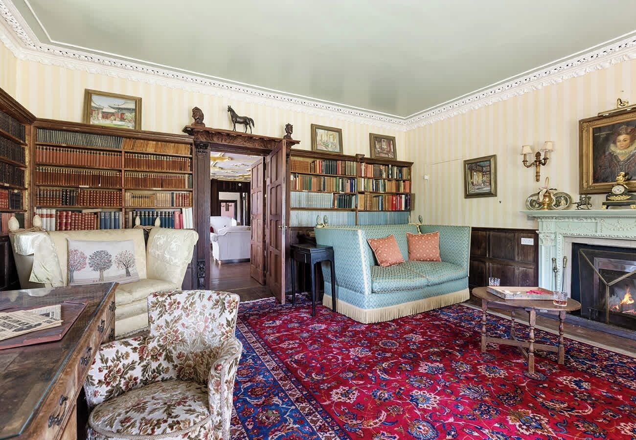 Une bibliothèque traditionnelle avec des étagères, une cheminée et des meubles classiques.