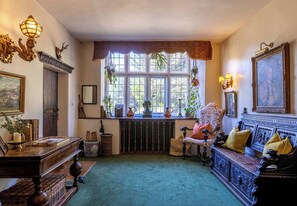 Ein traditionell eingerichtetes Zimmer mit großem Fenster, Kamin und klassischer Möbel.