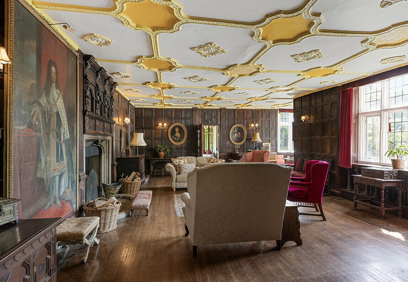 Una sala majestuosa con chimenea, techo decorado y muebles clásicos.