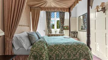 A bedroom with a four-poster bed, a bedside table, and a window with curtains.