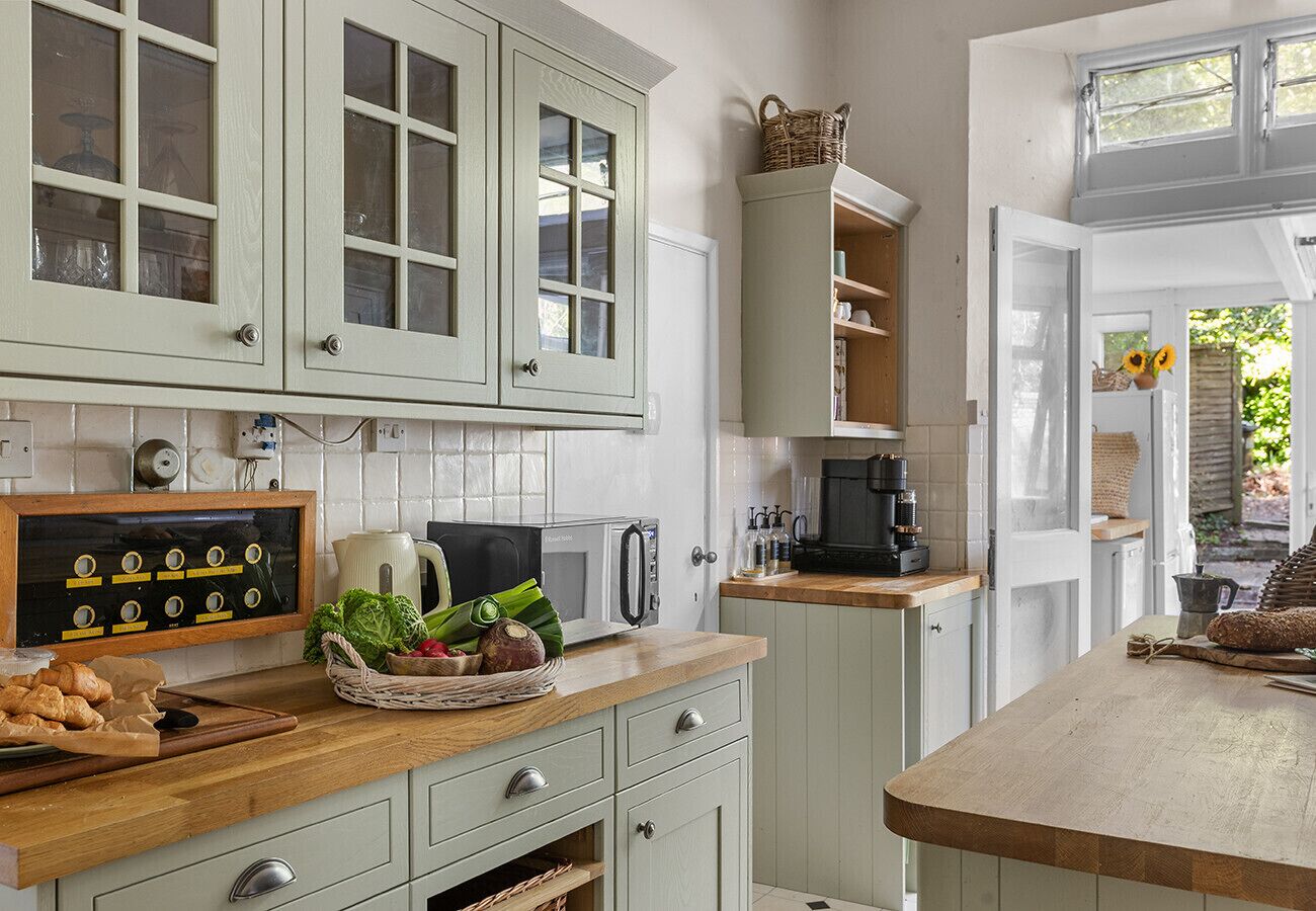A kitchen with white cabinets, a microwave, a coffee maker, and a wooden countertop.
