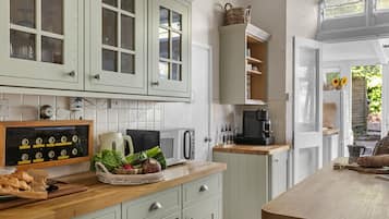 A kitchen with white cabinets, a microwave, a coffee maker, and a wooden countertop.