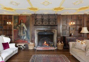 A traditional room with a fireplace, wooden paneling, and classic furniture. - Haremere Hall - A Jacobean Estate of Grandeur (Etchingham)