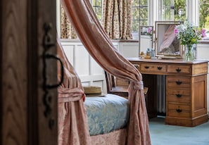 A bedroom with a canopy bed, a wooden dresser, and a window with curtains. - Haremere Hall - A Jacobean Estate of Grandeur (Etchingham)