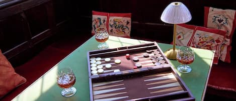 Backgammon-lauta on asetettu pöydälle huoneeseen, jossa on penkki ja tyynyjä.