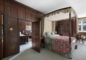 Un dormitorio tradicional con cama con dosel, un armario de madera y un escritorio con silla.