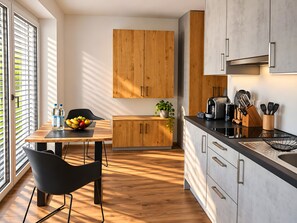 Une cuisine moderne avec des meubles en bois, une table à manger avec des chaises et une machine à café.