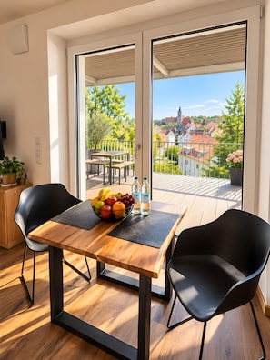 Een moderne eetruimte met een houten tafel, zwarte stoelen en een schaal met fruit.