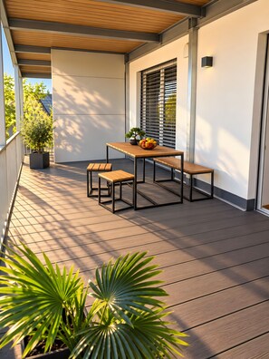 A wooden deck with a table and benches, surrounded by walls and a window with blinds.