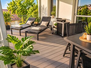 Un balcon avec deux fauteuils, une petite table et un pot de fleurs.