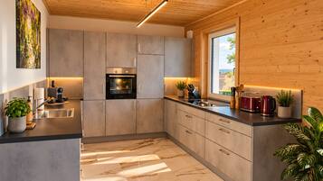Une cuisine moderne dotée d’un four encastré, d’appareils électroménagers en acier inoxydable et d’un sol en marbre.