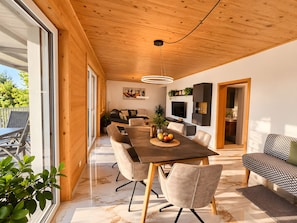 Um interior moderno com área de refeições, sofá, televisão e cozinha.
