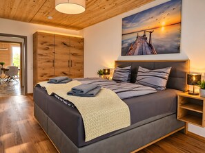 Quarto moderno com cama grande, guarda-roupa de madeira e uma pintura do pôr do sol.
