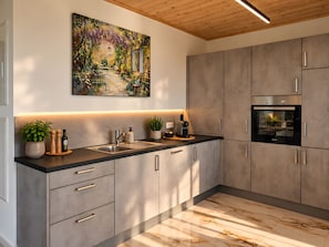 Cozinha moderna com uma ilha grande, eletrodomésticos embutidos e um quadro decorativo sobre a pia.